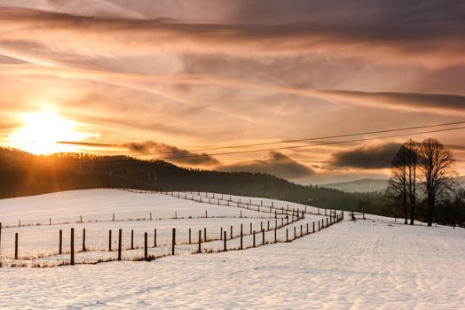 Beautiful Sunset over Snow Covered Farmland and Fields in Bieszczady, Poland.