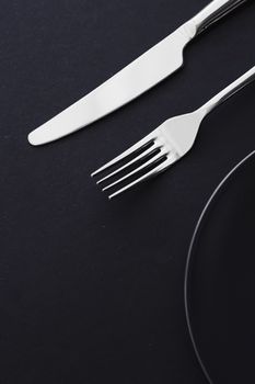 Empty plates and silverware on black background, premium tableware for holiday dinner, minimalistic design and diet concept