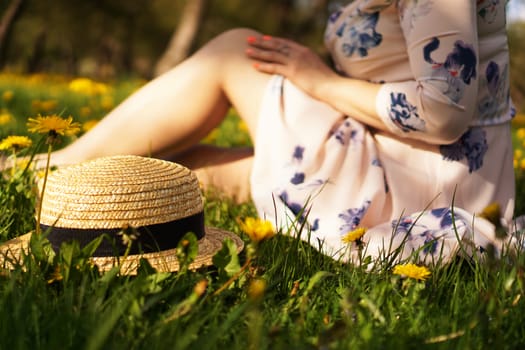 Woman with a straw hat in a flower field and green grass. Summer in the country. Focus on hat