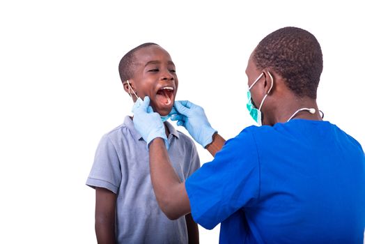 young man dentist in uniform examining the teeth of a little boy in the hospital.