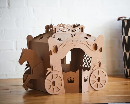 A horse and a carriage made of brown cardboard,where the horse is pulling the carriage