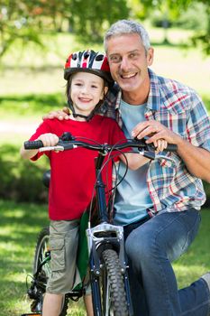 Happy little boy on his bike with his father on a sunny day