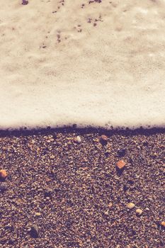 Sea wave foam on the beach sand. Marine summer background.