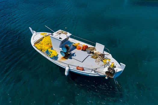 Aerial photo top view of small traditional fishing boat in tropical emerald and turquoise clear sea. Peloponnese, Greece