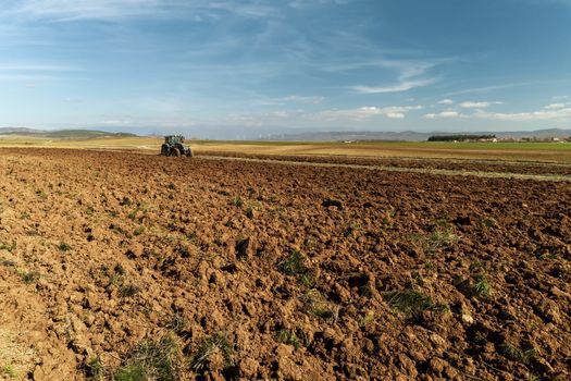 Aerial drone shot of a farmer in tractor seeding, sowing agricultural crops at field in the fertile farm fields of Kilkis in North Greece