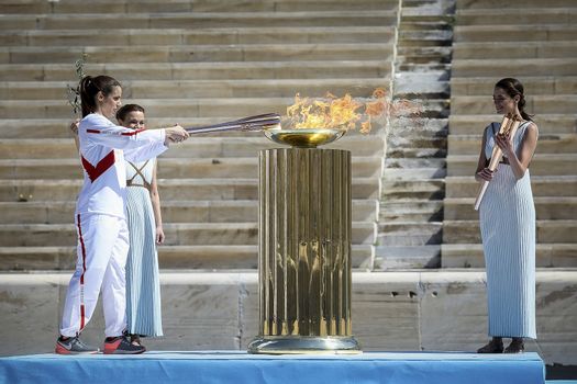 Athens, Greece - March 19, 2020: Olympic Flame handover ceremony for the Tokyo 2020 Summer Olympic Games at the Panathenaic  Stadium. Greek athlet K. Stefanidi (L) is seen lighting the cauldron