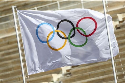 Athens, Greece - March 19, 2020: Olympic Flame handover ceremony for the Tokyo 2020 Summer Olympic Games at the Panathenaic Kallimarmaro Stadium. Olympics Flag