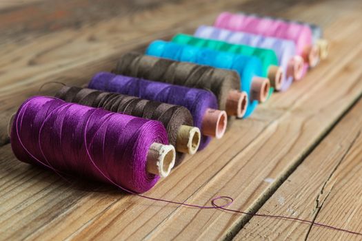 Spools of thread on wooden  background. Old sewing accessories. colored threads