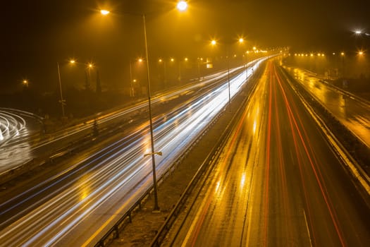 Speed Traffic - light trails on motorway highway at night with fog, long exposure abstract urban background