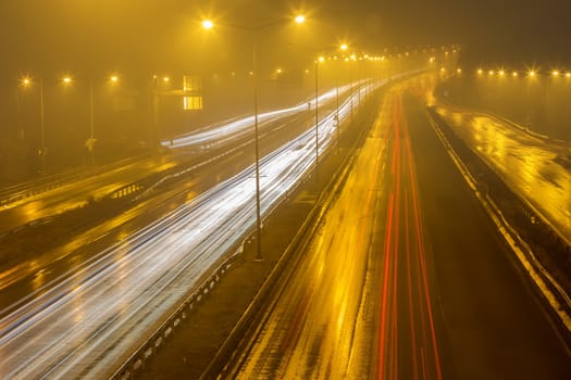 Speed Traffic - light trails on motorway highway at night with fog, long exposure abstract urban background
