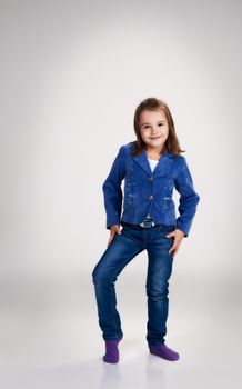 little girl in blue jeans and jacket posing standing in the studio