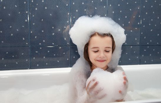 little girl playing with soap suds  in a bath closeup