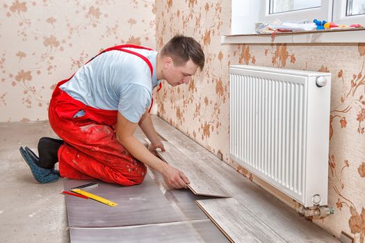 young handyman installing wooden floor in new house