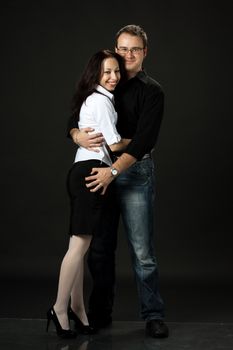 happy young couple posing in studio on black background