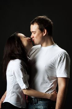 young family happy kissng in studio on black background