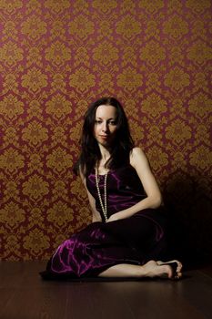 pretty young woman in vinous dress posing sitting on the floor