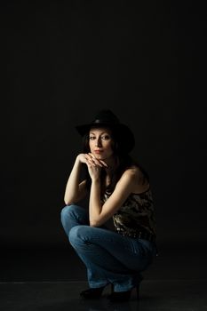 pretty woman in black hat posing sitting in studio
