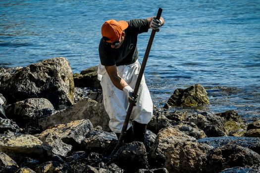 Salamis, Athens, Greece - Sept 13, 2017: Workers try to clean up oil that has washed ashore, on a beach of Salamis island near Athens, after an old tanker sank close to Salamis island