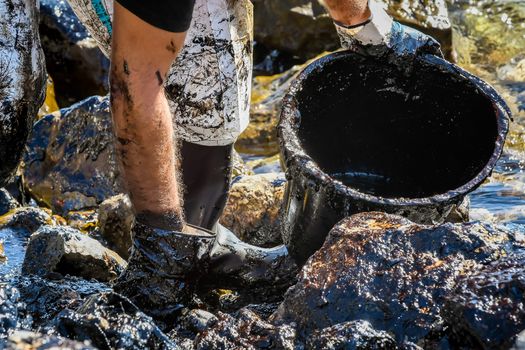 Salamis, Athens, Greece - Sept 13, 2017: Workers try to clean up oil that has washed ashore, on a beach of Salamis island near Athens, after an old tanker sank close to Salamis island 