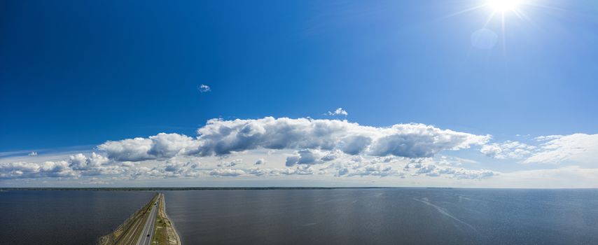 Aerial view of the amazing big river with dam under beautiful cloudy blue sky. Europe, Ukraine, Kremenchuk Reservoir, Dnieper or Dnipro River. Spring sunrise time.