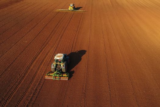 Aerial shot of  Farmer with a tractor on the agricultural field sowing. tractors working on the agricultural field in spring. Cotton seed