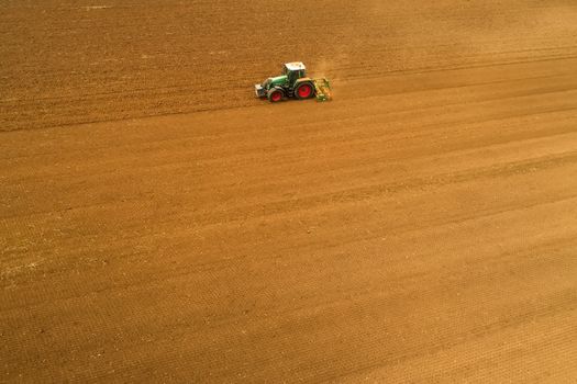 Aerial shot of  Farmer with a tractor on the agricultural field sowing. tractors working on the agricultural field in spring. Cotton seed