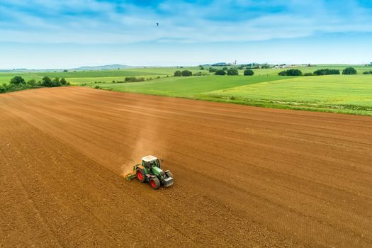 Aerial shot of  Farmer with a tractor on the agricultural field sowing. tractors working on the agricultural field in spring. Cotton seed