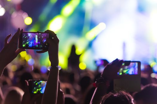 Hand with a smartphone records live music festival, Taking photo of concert stage, live concert, music festival, happy youth, luxury party, landscape exterior