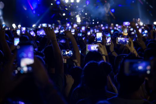 Hand with a smartphone records live music festival, Taking photo of concert stage, live concert, music festival, happy youth, luxury party, landscape exterior