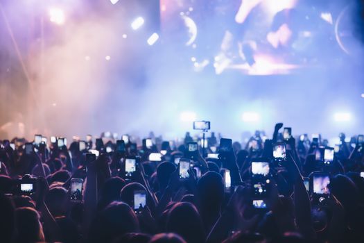 People taking photographs with smart phone during a public music concert