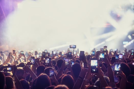 People taking photographs with smart phone during a public music concert