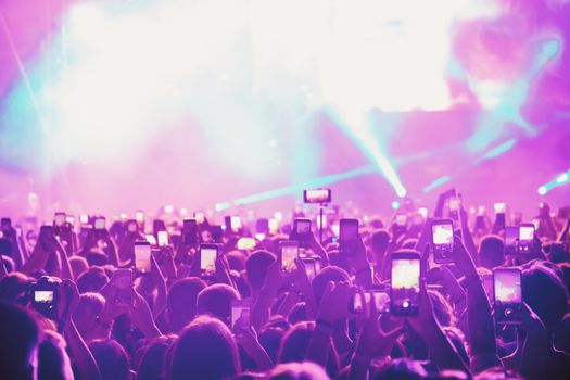 People taking photographs with smart phone during a public music concert