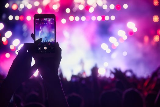 People taking photographs with smart phone during a public music concert