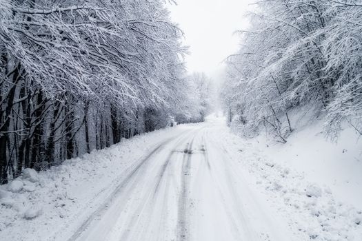 Aerial view of snowy forest with a road in the area of Naoussa in northern Greece.  Captured from above with a drone.