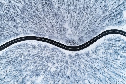 Aerial view of a provincial road passing through a snowy forest ιn Chalkidiki, northern Greece