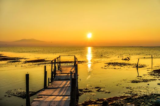 Long exposure of magic sunrise over the ocean with and a wooden bridge.