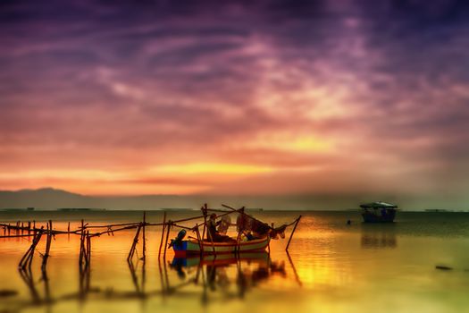 View of a beautiful sky reflecting on the ocean and a fisherman on his boat hanging fishing nets.