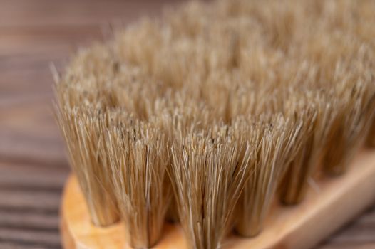 Vintage shoe brush with wooden handle on wooden background. Close up view with small depth of field.