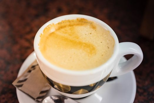 Cappuccino or latte milk coffee in white cup and saucer on a marble table