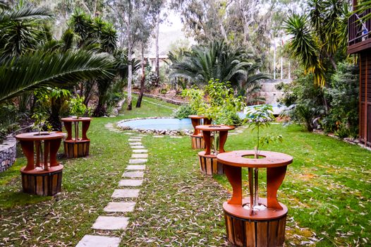 Tropical garden with palm trees and wooden tables on the island of Crete in Greece