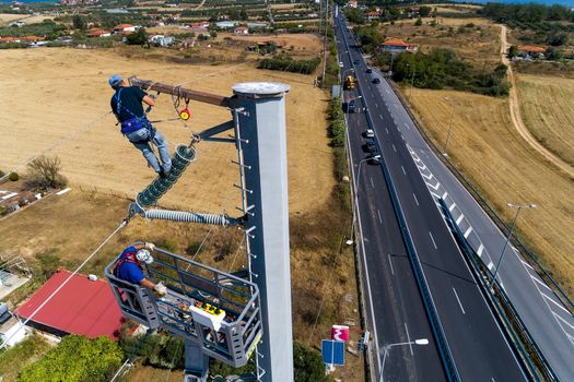 Chalkidiki, Greece - July 12, 2019: Electricians are climbing on electric poles to install and repair power lines after the fierce storm that struck the area