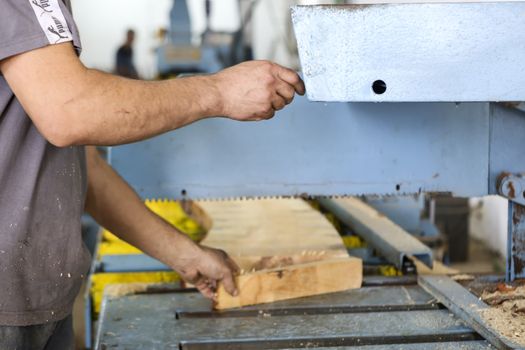 Thessaloniki, Greece, July 8, 2015: Craftsmen cut a piece of wood at a woodworking factory in Greece. Wood and furniture production plant, industrial factory with tools and objects.