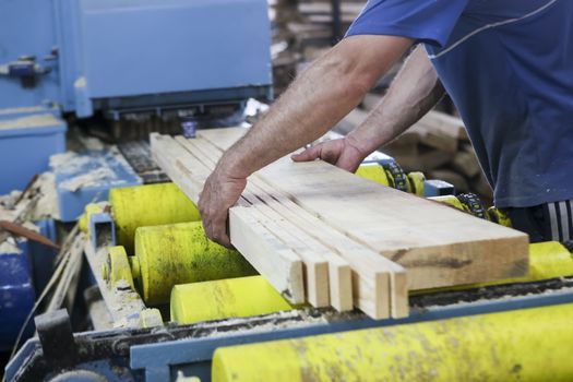 Thessaloniki, Greece, July 8, 2015: Craftsmen cut a piece of wood at a woodworking factory in Greece. Wood and furniture production plant, industrial factory with tools and objects.