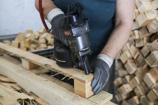 Thessaloniki, Greece, July 8, 2015: Craftsman puts nails in a piece of wood at a woodworking factory in Greece. Wood and furniture production plant, industrial factory with tools and objects.