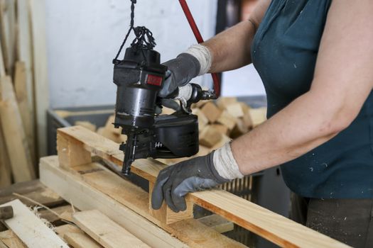 Thessaloniki, Greece, July 8, 2015: Craftsman puts nails in a piece of wood at a woodworking factory in Greece. Wood and furniture production plant, industrial factory with tools and objects.