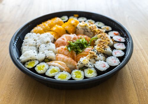 A fresh platter of sushi with rice and fish on wooden background