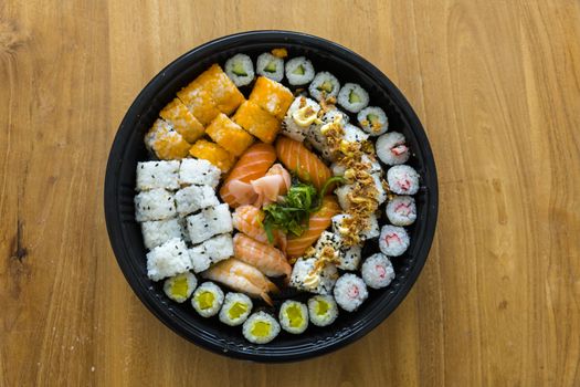 A fresh platter of sushi with rice and fish isolated on wooden table