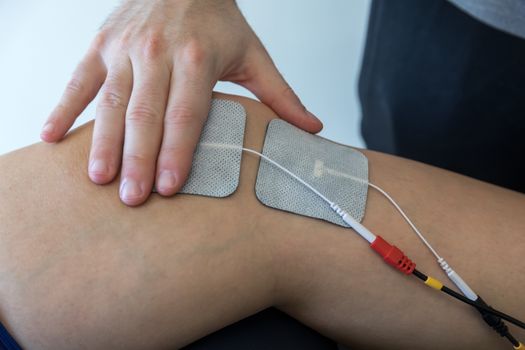 electronic therapy on knee used to treat pain. selective focus