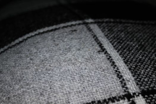 The texture of the knitted plaid in a cell in gray-black