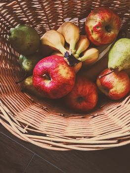 Organic apples, pears and bananas on rustic in a wicker basket, fruits farming and agriculture